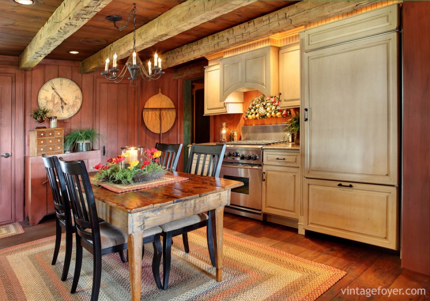 Looking for something bold? Red-stained cabinetry gives a warm, vibrant look to any small space. Combine that with exposed beams, black accent chairs, and a stunning flush fridge. 