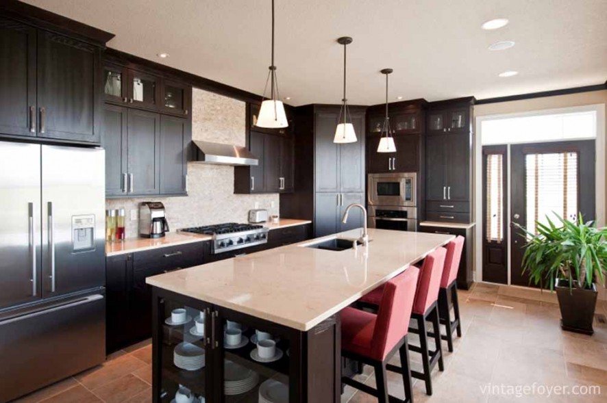 A black and white kitchen can feel starved of colour, but you should consider that adding bold and bright colours can completely change the colour of the entire room. Subtle changes like these muted red chairs and a large plant add subtle colours without sacrificing the kitchen’s stylish black and white theme.