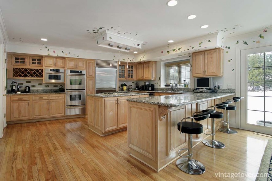 Light toned hardwood cabinetry and island, beautiful black speckled marble countertop, and high end stainless steel appliances. 