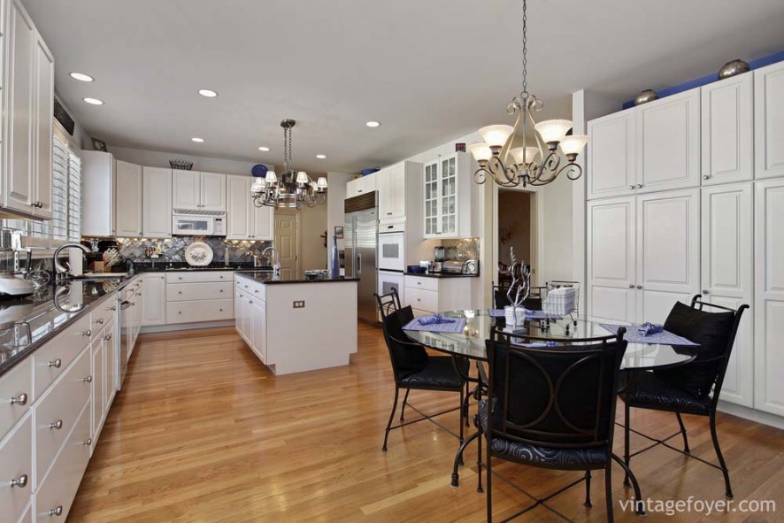 Light toned hardwood flooring, beautiful black marble countertops, and white custom cabinetry.