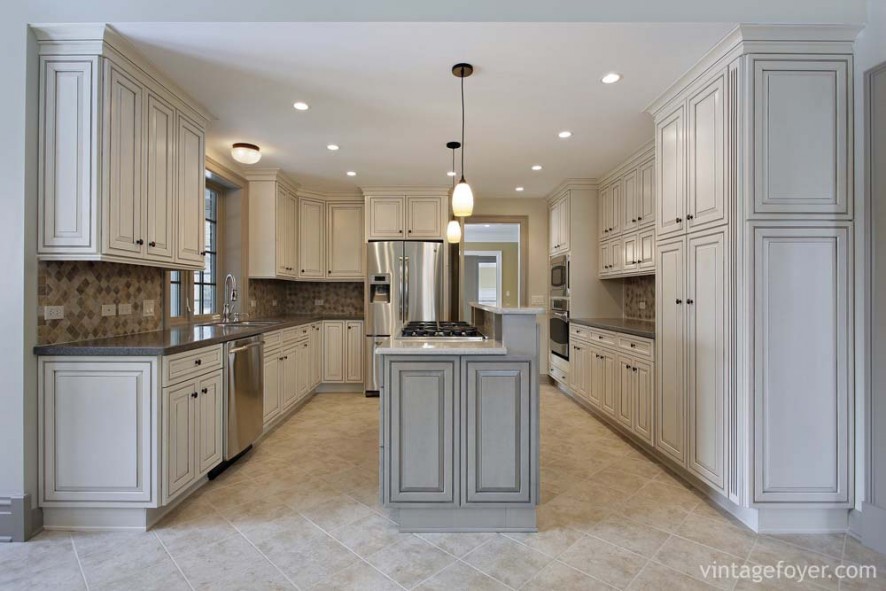 Custom multi-colored porcelain backsplash, traditionally styled white cabinetry and island, contrasting white marble countertops on the island with black countertops on the cabinetry. 