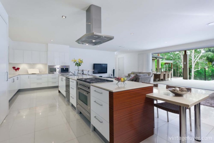 Large open concept modern designed kitchen, stainless steel appliances, and glossy white porcelain tile. 