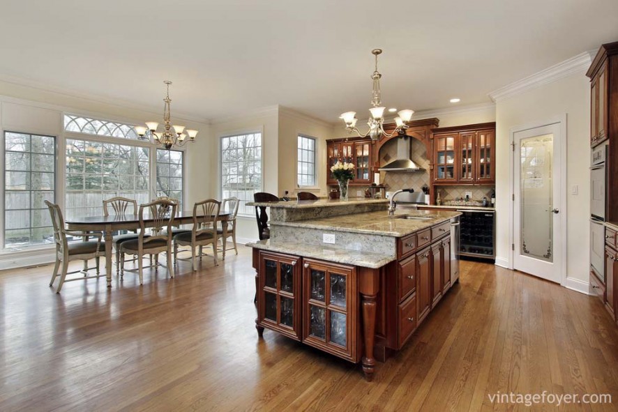 Large open concept, beautiful custom cabinetry with white/grey marble countertops, stainless steel appliances, and light toned hardwood flooring. 