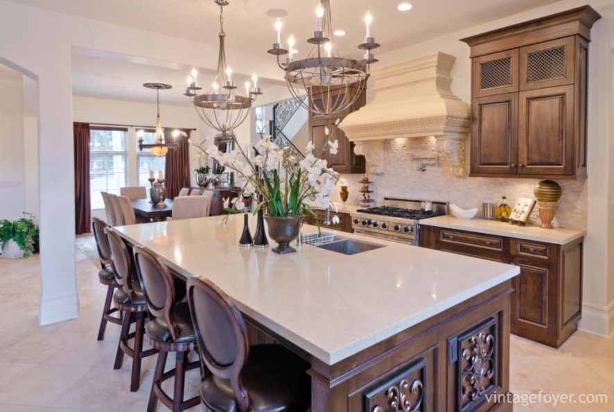 Custom designed island and cabinetry with white quartz countertops, custom oven hood with beautiful architectural details, elegant cream toned porcelain tile flooring. 