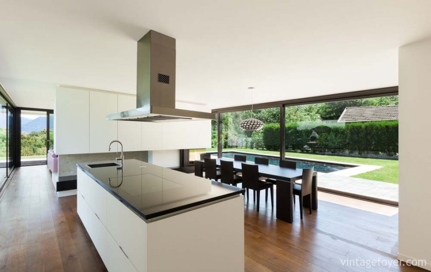 Contemporary white cabinetry design, sleek black quartz countertops, and dark toned hardwood flooring.
