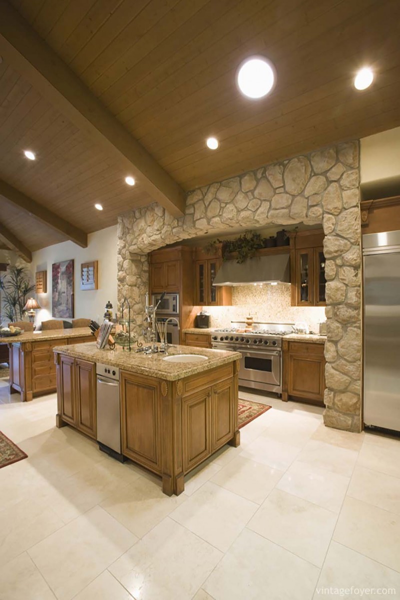 Custom stone archway with inset appliance area, beautiful cream toned tile, and medium toned cabinetry. 