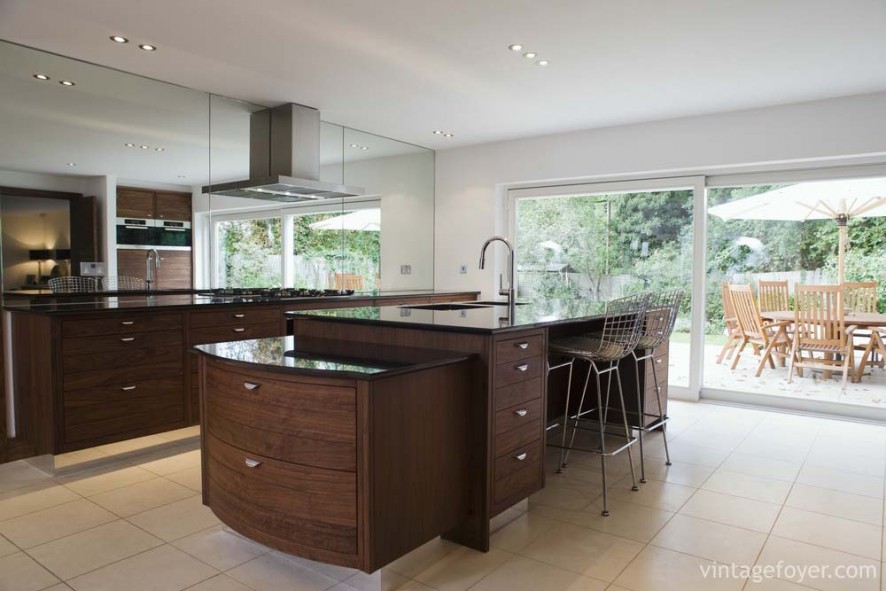 Dark toned modern style cabinetry, cream colored porcelain tile, black quartz countertop and natural lighting.