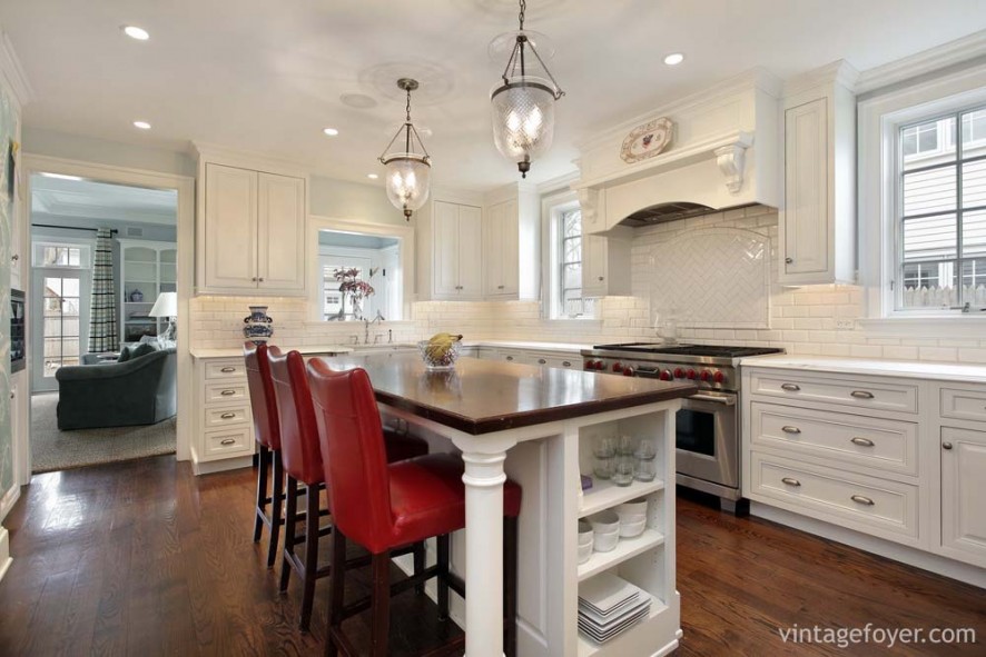 Custom white tile backsplash with herringbone pattern, dark contrasting hardwood flooring, traditional designed white cabinetry with architectural accents. 