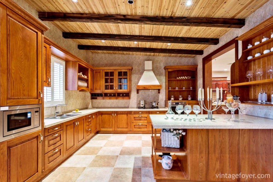 Multi-colored tile flooring, medium toned traditional style cabinetry and island with quartz countertops. 