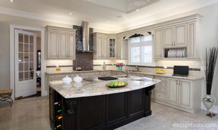 Black island with white speckled marble countertop, custom traditional cabinetry with the same beautiful countertop, custom black backsplash, and high end appliances. 